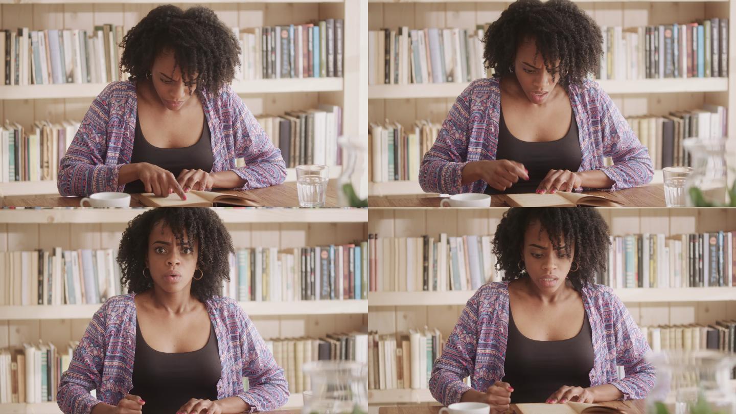一位非洲裔女性在客厅里读着迷人的书。情节扭曲的情绪反应-看着相机