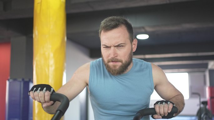 聚焦男性在健身房慢动作视频中使用静态自行车