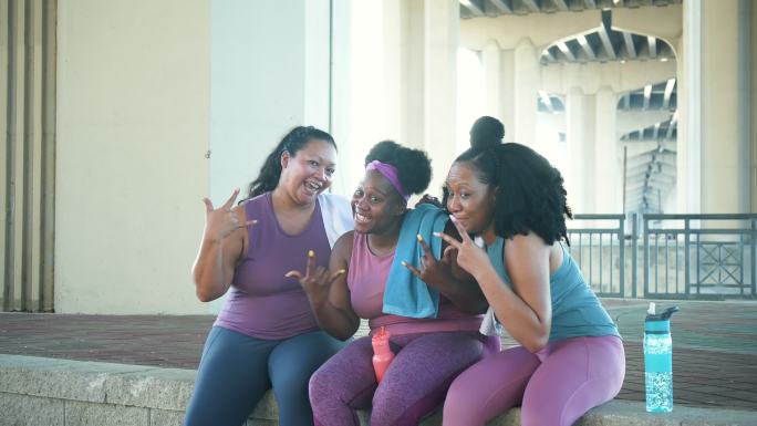 多种族女性在锻炼后坐在一起，手语