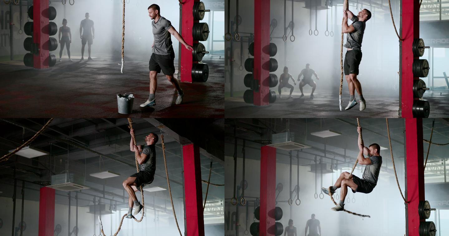 强壮的男人在健身房里爬绳子。