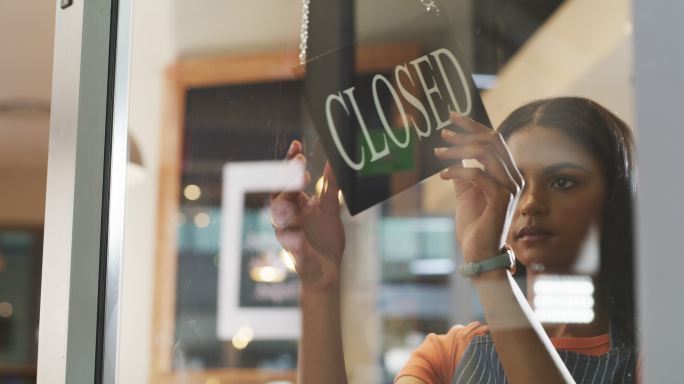一名年轻女子在咖啡馆将开放标志变为关闭的4k视频片段