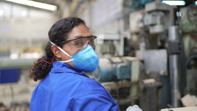 一位中年女性在工厂工作的肖像-使用面罩