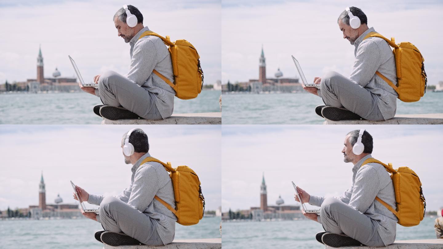 这名男子在威尼斯度假时，一边听音乐一边在笔记本电脑上工作。
