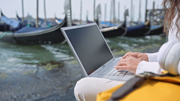 一名妇女在威尼斯度假时用笔记本电脑工作。