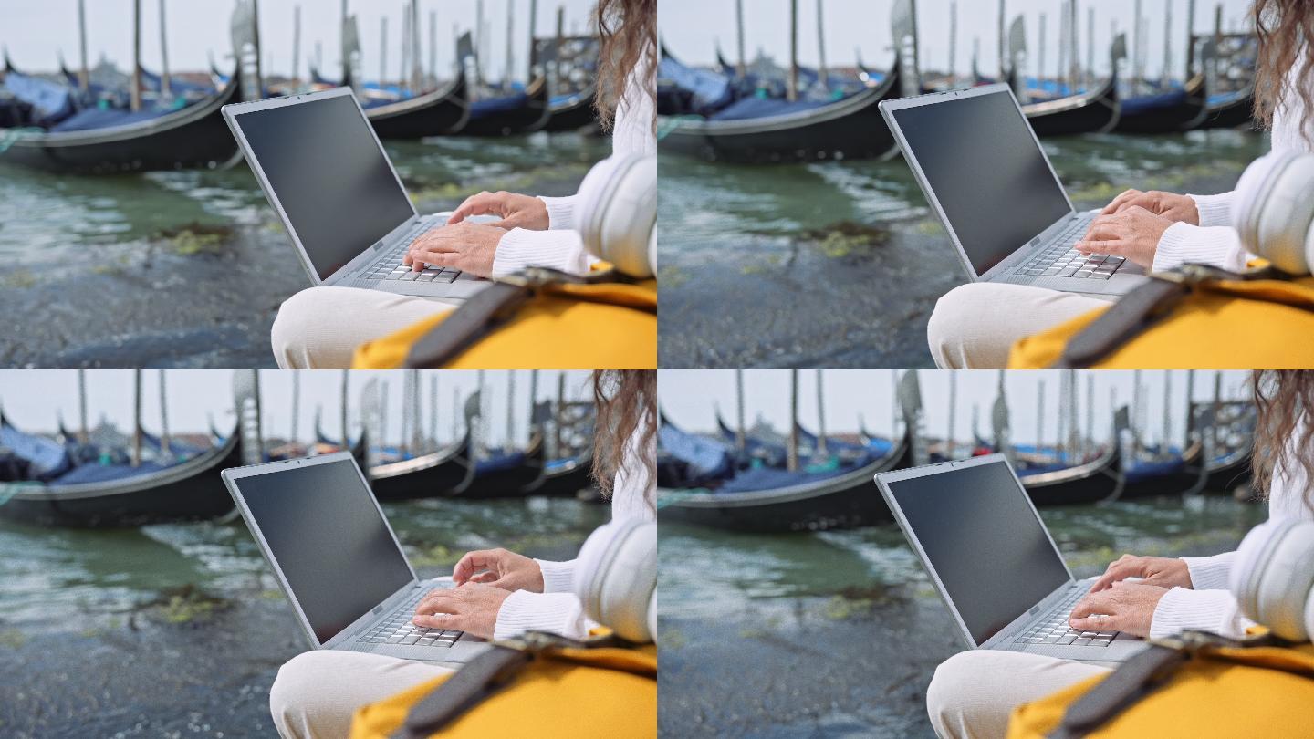 一名妇女在威尼斯度假时用笔记本电脑工作。