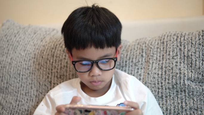 亚洲男孩玩智能手机。