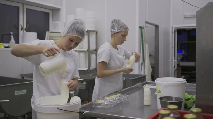 两名在乳制品生产线工作的妇女在瓶装酸奶