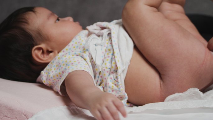 亚洲母亲在家里为4个月大的女婴亲手换尿布。