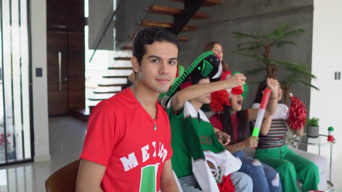 一个十几岁的拉丁男孩与朋友在家观看墨西哥足球队比赛的照片