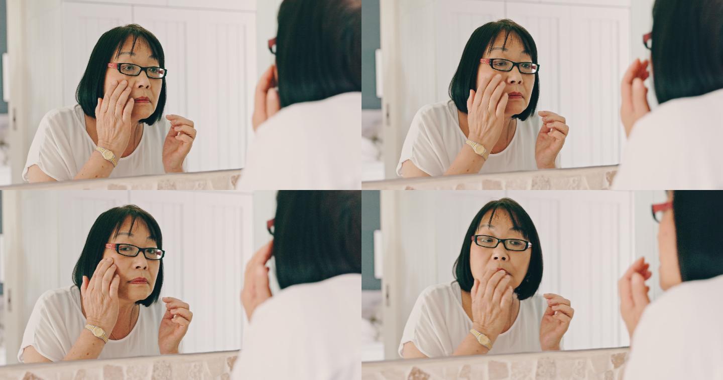 亚洲资深女性早上在家准备好护肤品。亚洲老妇人在家里对着镜子欣赏自己的皮肤