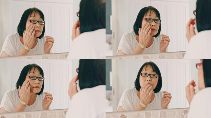 亚洲资深女性早上在家准备好护肤品。亚洲老妇人在家里对着镜子欣赏自己的皮肤
