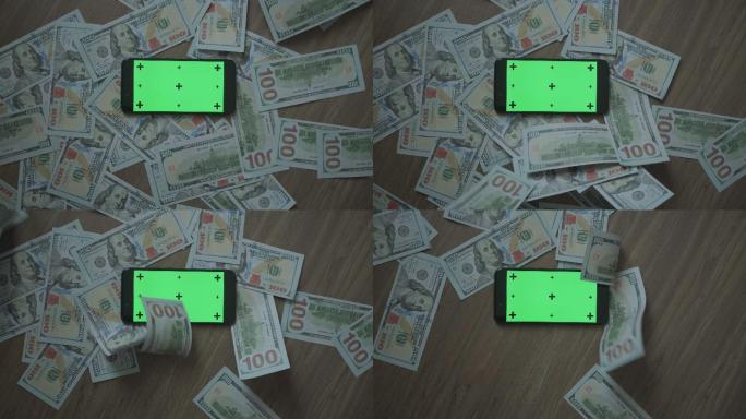钱落在绿色屏幕智能手机附近
