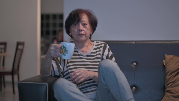 亚裔中国老年女性在周末闲暇时间独自在家看电视
