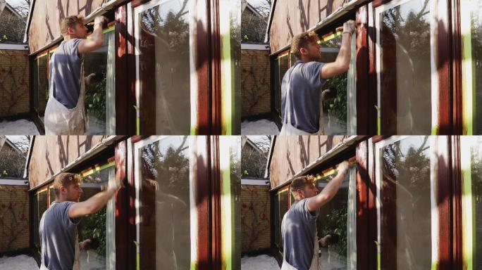 男油漆工在房屋外部喷涂窗饰
