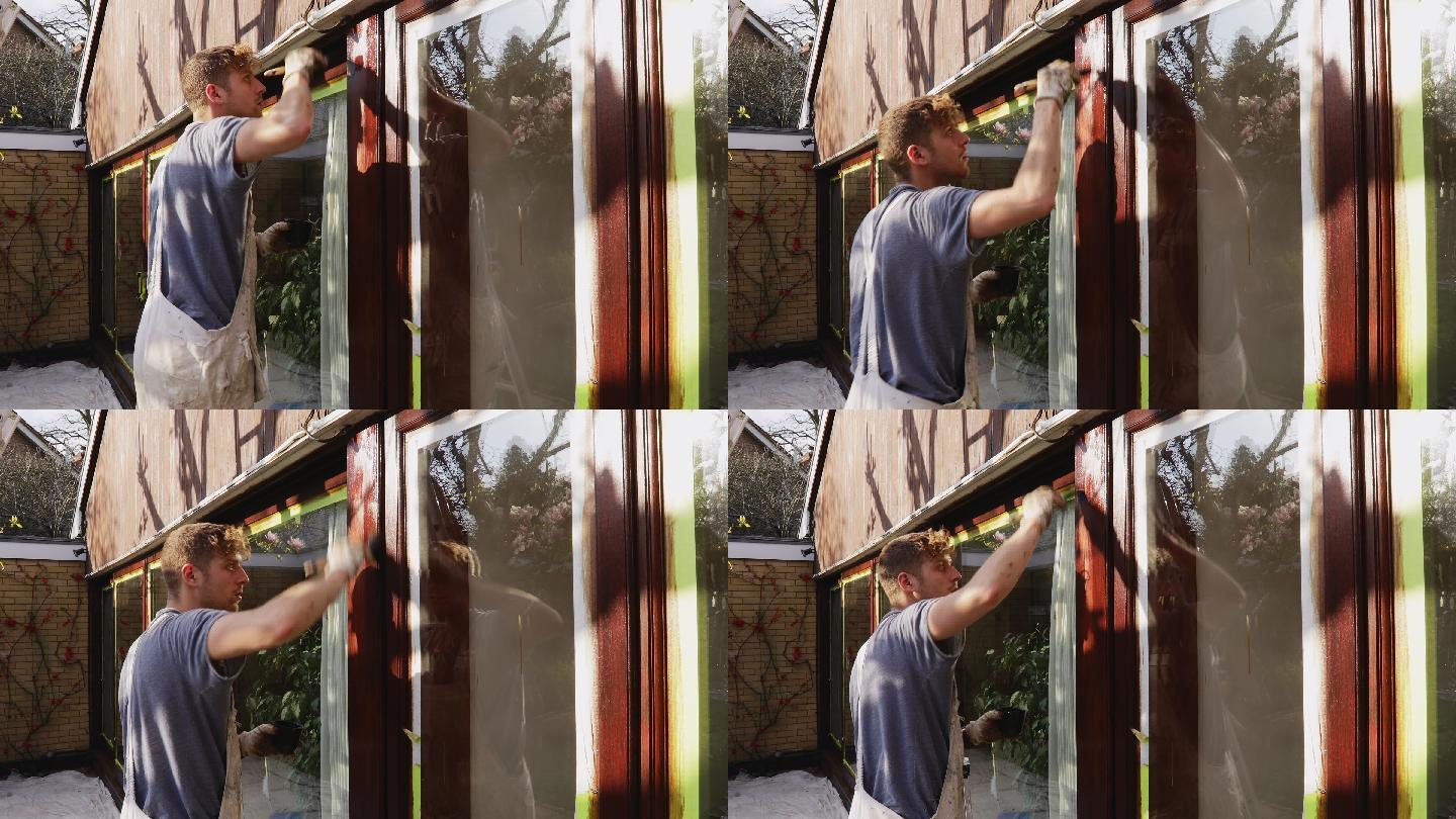 男油漆工在房屋外部喷涂窗饰