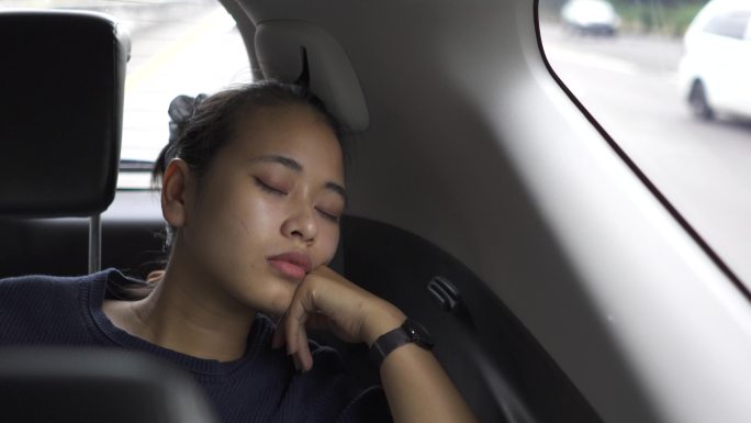疲惫的年轻女子睡在汽车后座上