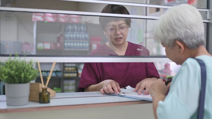 亚裔华裔老年女性用信用卡支付医疗费用NFT诊所女护士手持信用卡读卡器