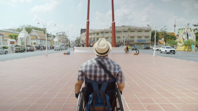 曼谷轮椅旅游地标概念。亚洲男性游客在曼谷的巨型摇摆地标拍照留念