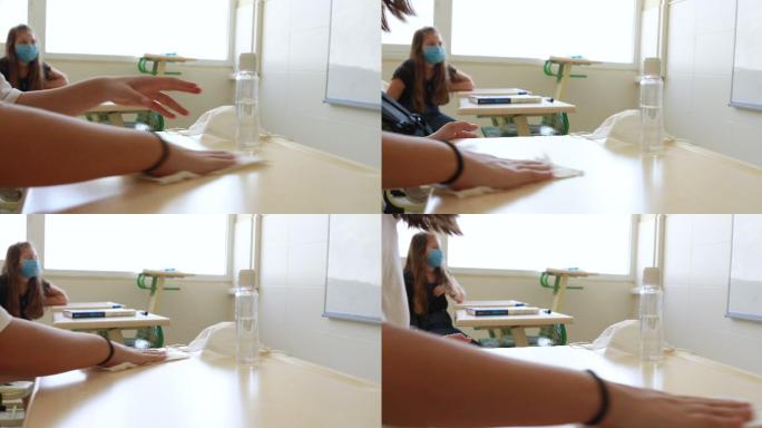 带口罩的女生在教室里用消毒抗菌凝胶清洁双手和桌子