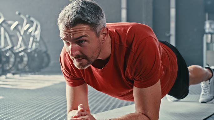 一个英俊的成熟男子在健身房锻炼时保持着支架式姿势的4k视频片段