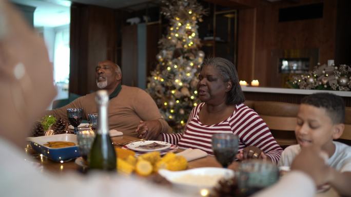 圣诞节午餐或晚餐时，家人在家与家人一起祈祷