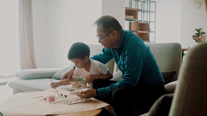 亚洲男孩和祖父画玩具模型飞机（慢动作）