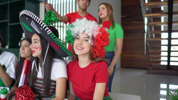 一位十几岁的拉丁女孩与朋友在家观看墨西哥足球队比赛的照片