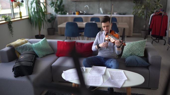 男小提琴手在家里的沙发上清洗小提琴