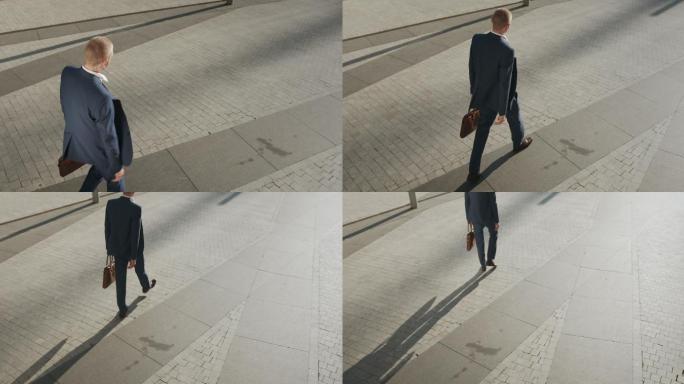 日落时分，一位身穿深蓝色西装、棕色皮革笔记本电脑包的年轻商人沿着铺好的街道经过