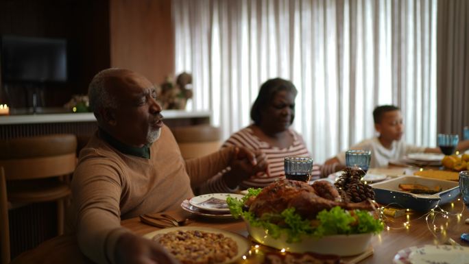 圣诞节午餐或晚餐时，家人在家与家人一起祈祷