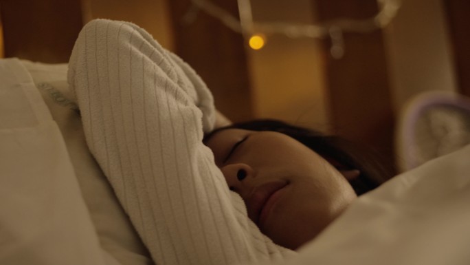 快乐的亚洲女孩睡在家里卧室的床上，生活方式的概念。