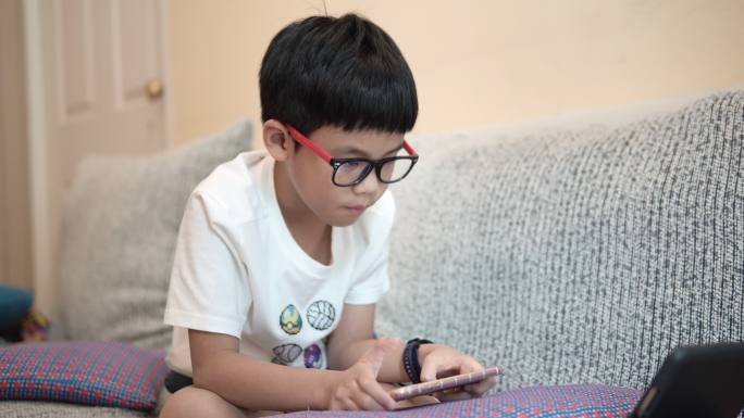 亚洲男孩在智能手机上玩游戏。