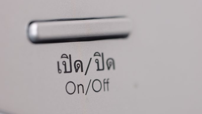 泰语洗衣机上手指按下打开/关闭按钮的侧视图