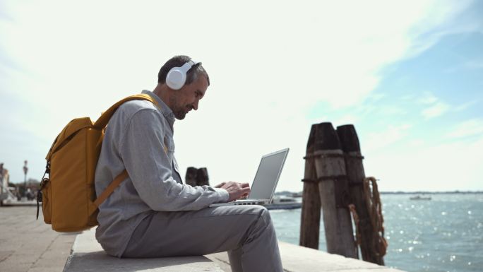 这名男子在威尼斯度假时，一边听音乐一边在笔记本电脑上工作。