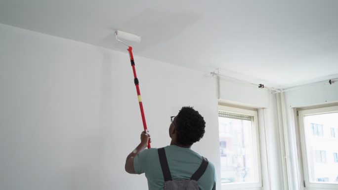 非裔美国专业画家在室内粉刷墙壁
