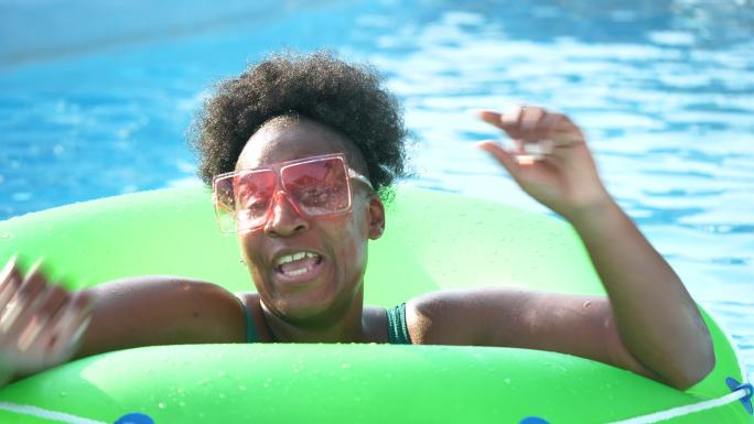 一位非洲裔美国妇女漂浮在懒洋洋的河面上，挥手致意