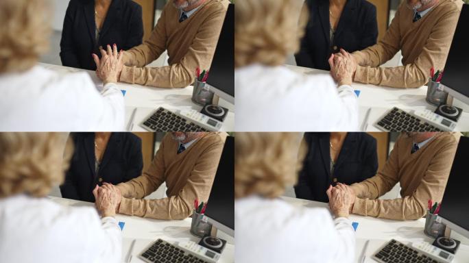 一位面目全非的医生在会诊时与患者手牵手的照片