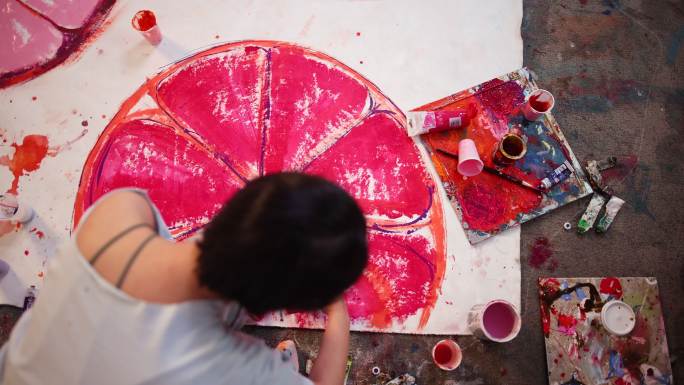 才华横溢的女画家用紫色颜料在画布上绘画的高角度视图