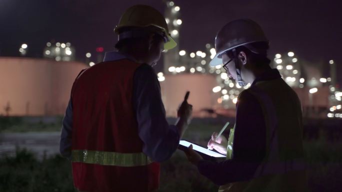 4K分辨率工程师石化亚洲男子在炼油厂油气工业工厂内工作到深夜，努力使用智能平板电脑