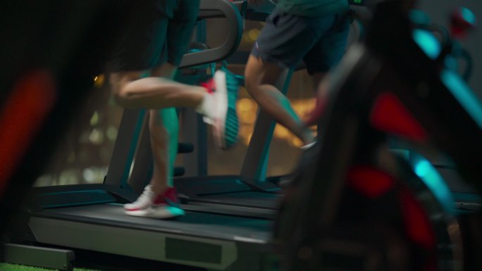 后视图低截面男子汉双腿一起在健身房跑步机上跑步面对城市路灯