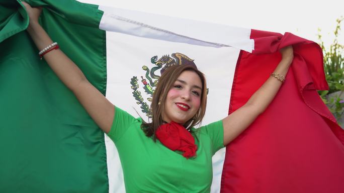 一个十几岁的拉丁女孩举着墨西哥国旗的肖像