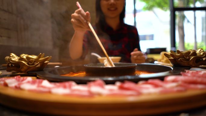 亚洲年轻女子在餐厅享用中国火锅