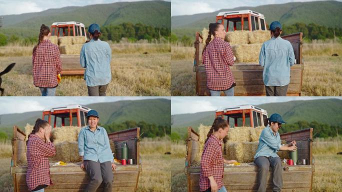 两名女农民在农场休息，在拖拉机拖车上休息，并互相交谈
