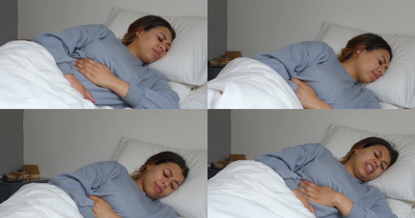 一名年轻女子在家躺在床上时胃痛的4k视频片段