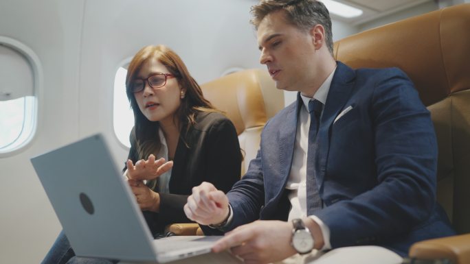 坐飞机旅行时，商人和女商人乘客在笔记本电脑上工作。