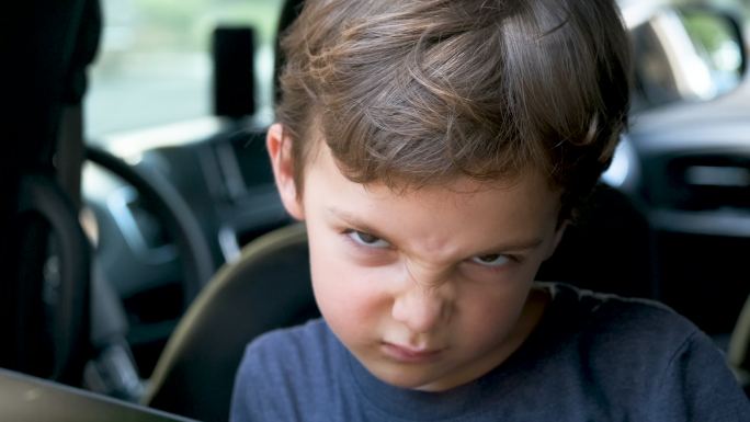 非常沮丧沮丧的小男孩透过车窗看，他不想回学校