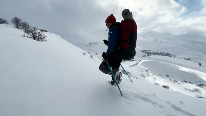 冬天背着背包在山上徒步旅行的男人