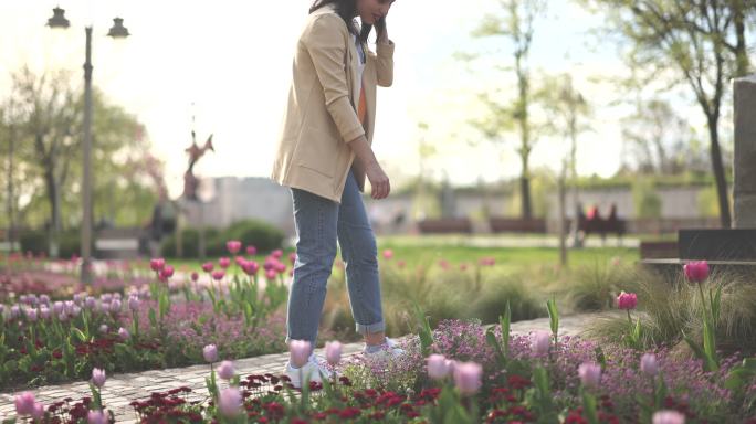 城市公园里闻花香的年轻女子