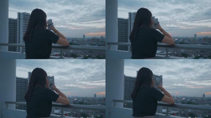千禧一代亚洲年轻女性在屋顶上看着曼谷，用手机在社交媒体上发帖拍照，感觉很孤独