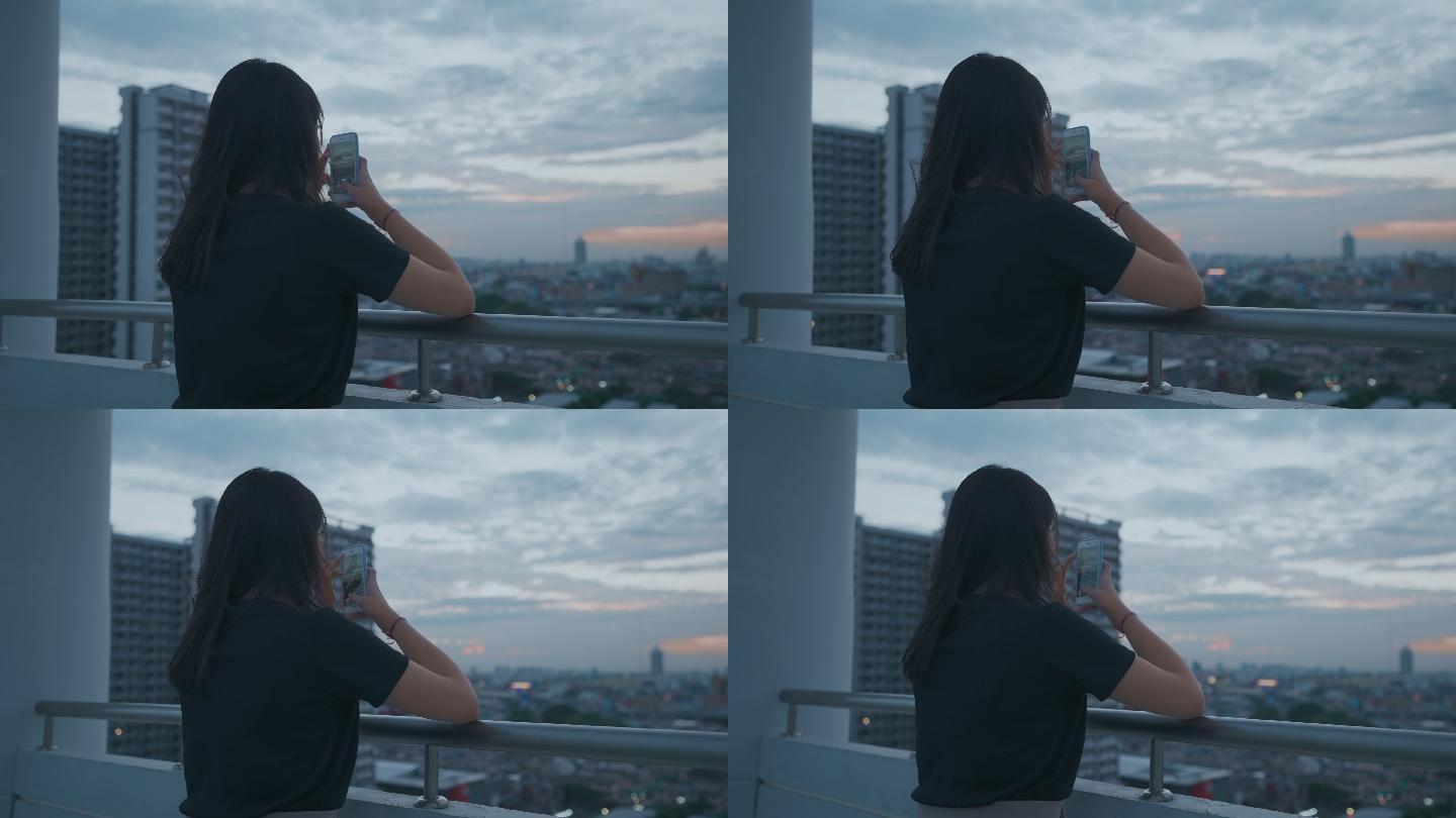 千禧一代亚洲年轻女性在屋顶上看着曼谷，用手机在社交媒体上发帖拍照，感觉很孤独